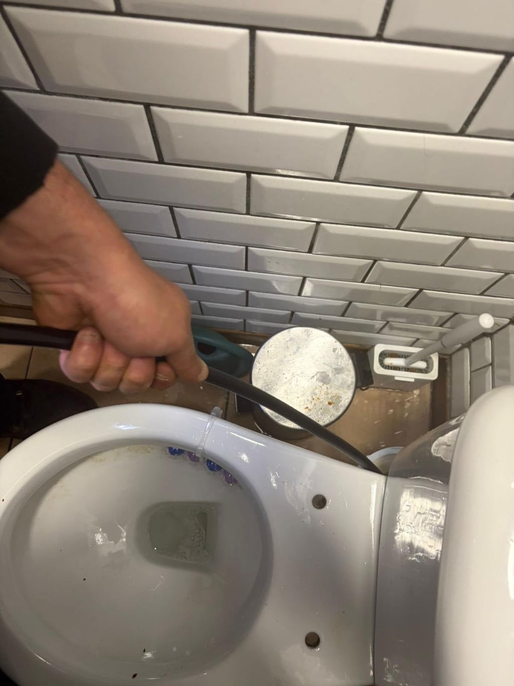 Main de technicien Nero Canalis tenant un furet souple lors d’un débouchage de WC à Bruxelles